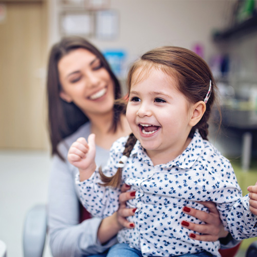 daughter playing on moms lap at dentist