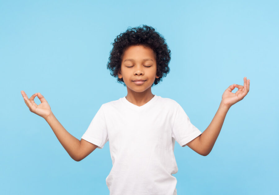 Black boy in a white t-shirt holds a zen pose as he relaxes 