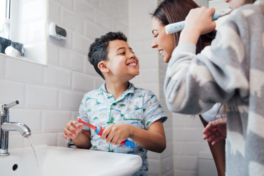 A young boy smiles at his mom after brushing his teeth in their bathroom