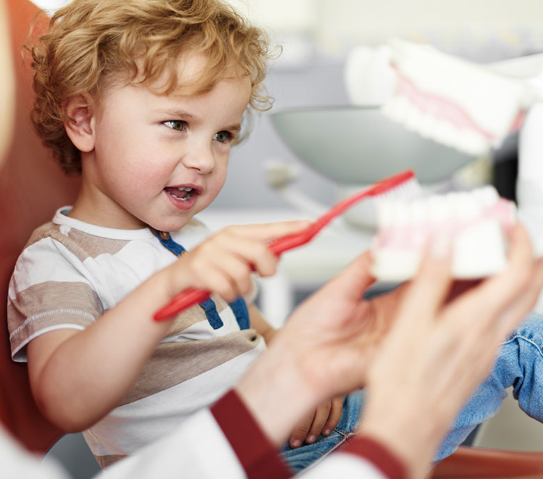 little boy practicing brushing teeth at dental office