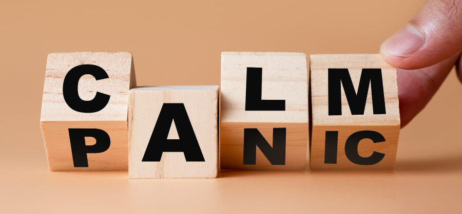 A finger turns 4 wooden blocks from PANIC to CALM against a brown background