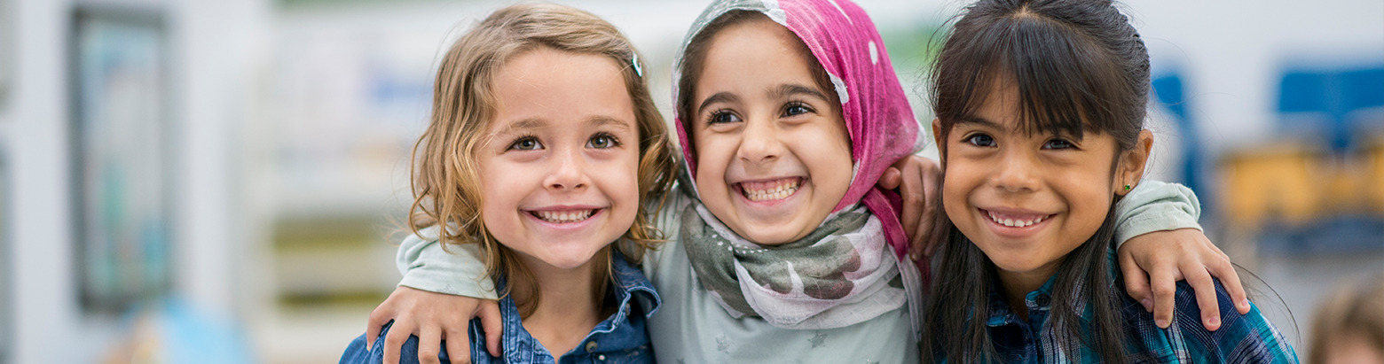 three young girls hugging and smiling