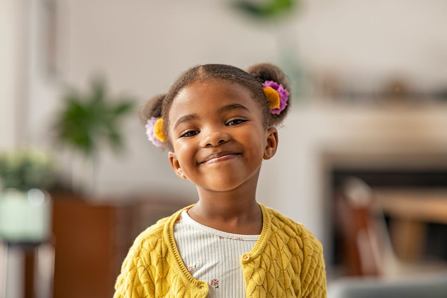 Smiling young Black girl wearing a yellow sweater
