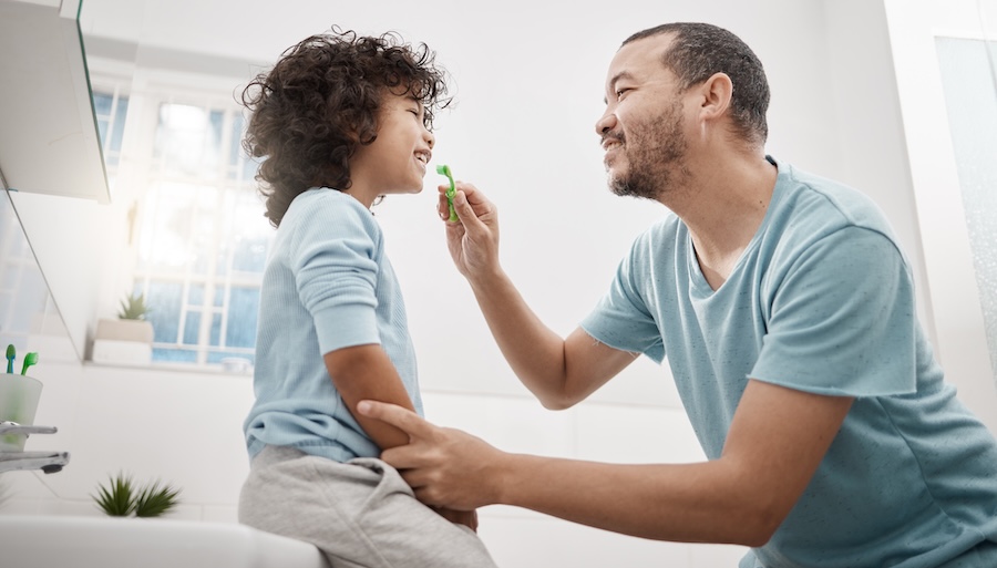 dad helping kid with brushing and flossing